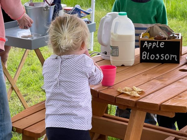 A young child has a snack at a picnic table